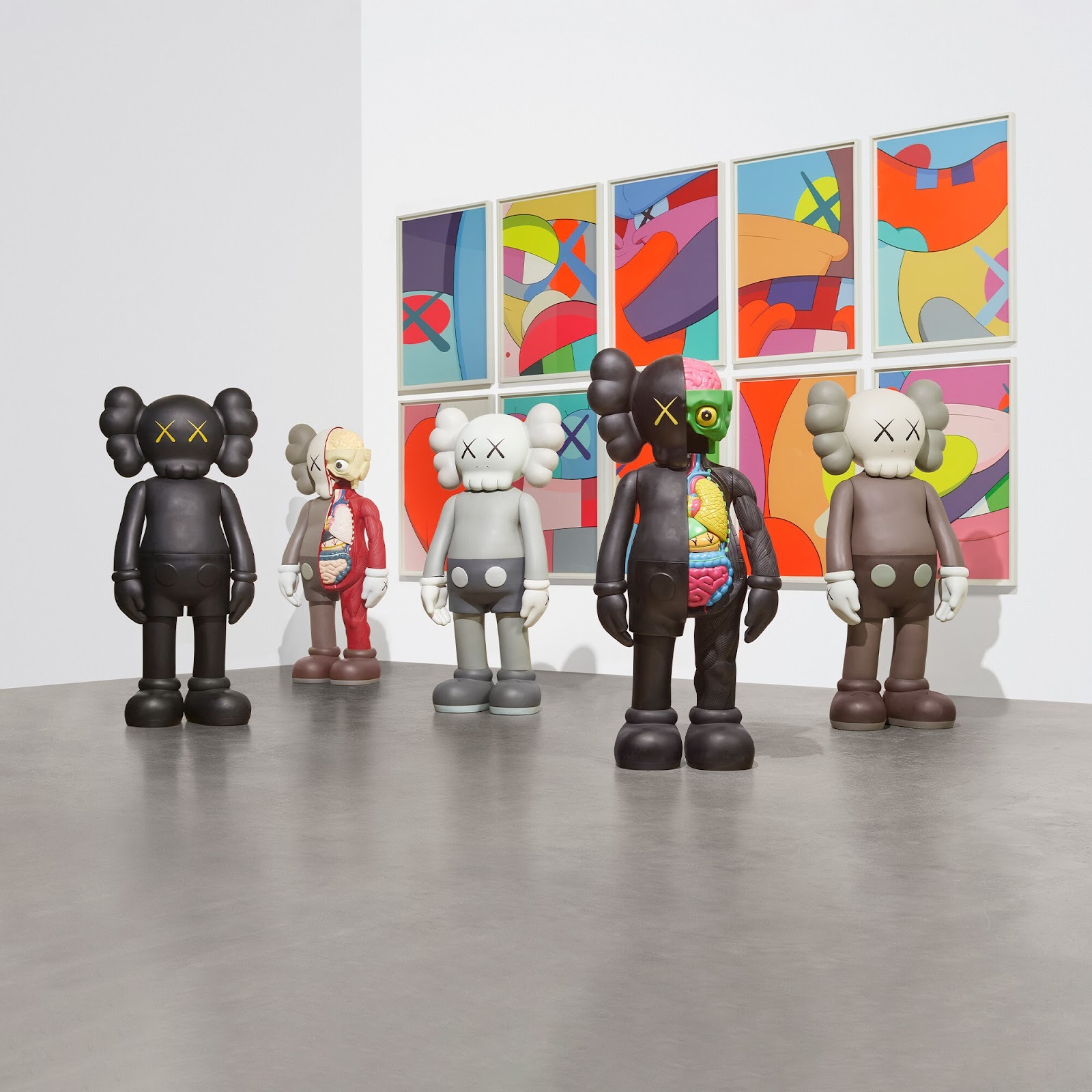 A collection of five 4 Ft Kaws Statues from the Companion figures series stand in the center of a gallery space.